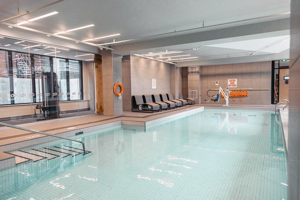 a swimming pool in a hotel with chairs and a glass door