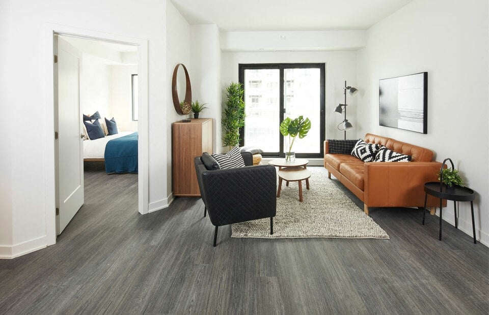 a living room with a couch and chair and a bed in the background