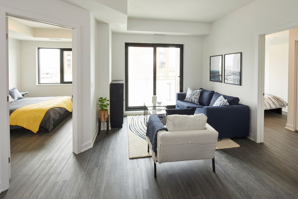 a living room with a couch and a chair in front of a bedroom