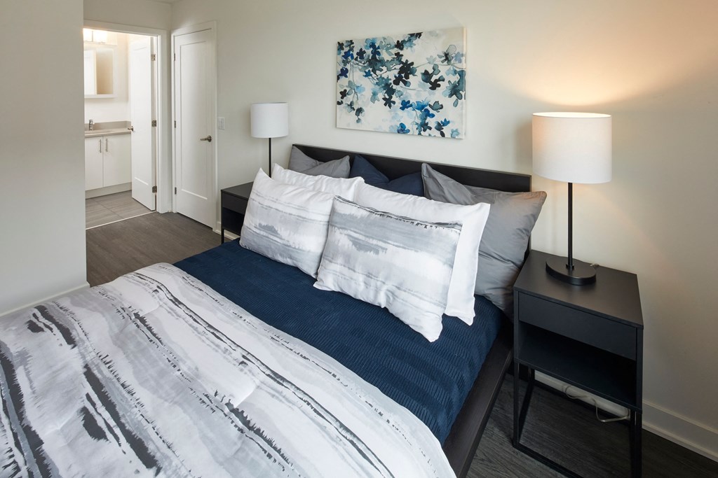 a bedroom with a bed with blue and white pillows and a table with lamps