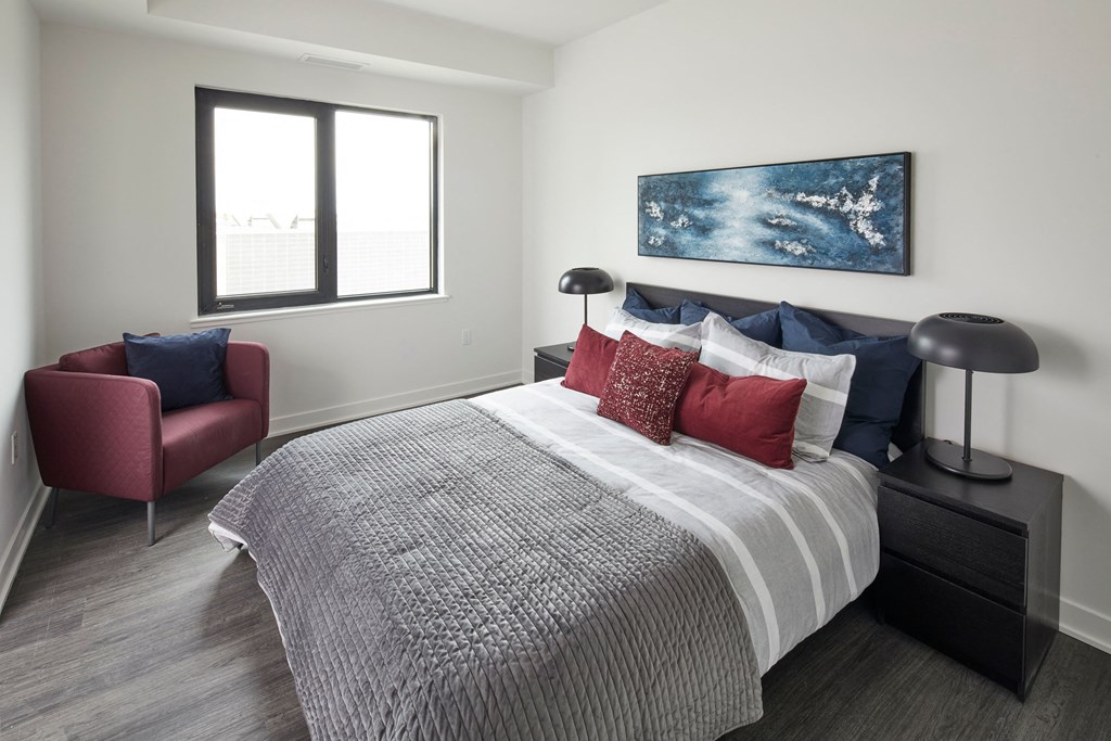 a bedroom with a bed and a chair and a window