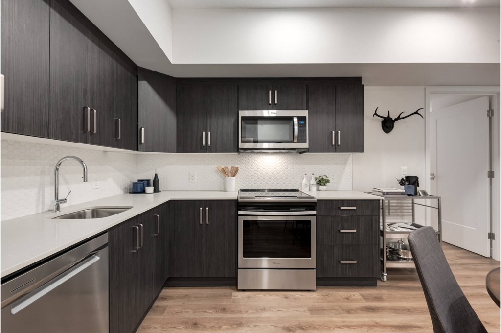 A modern kitchen with dark wood cabinets and stainless steel appliances.