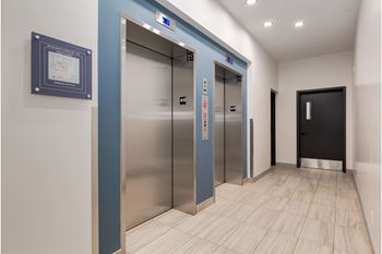 Two elevators in a hallway with a plaque on the wall.
