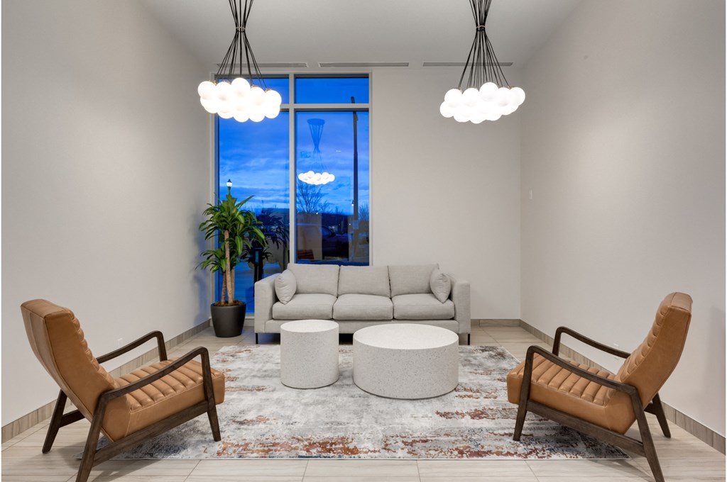 A living room with a large window, a sofa, a chair, a table, and a rug.