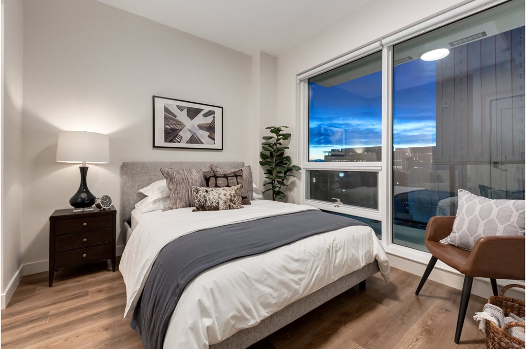 A bedroom with a large bed and a view of the city through the window.