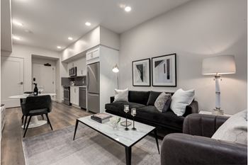 A modern living room with a black couch and a glass coffee table.