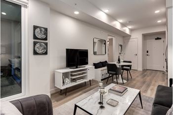 A modern living room with a grey sofa, a white coffee table, and a television.