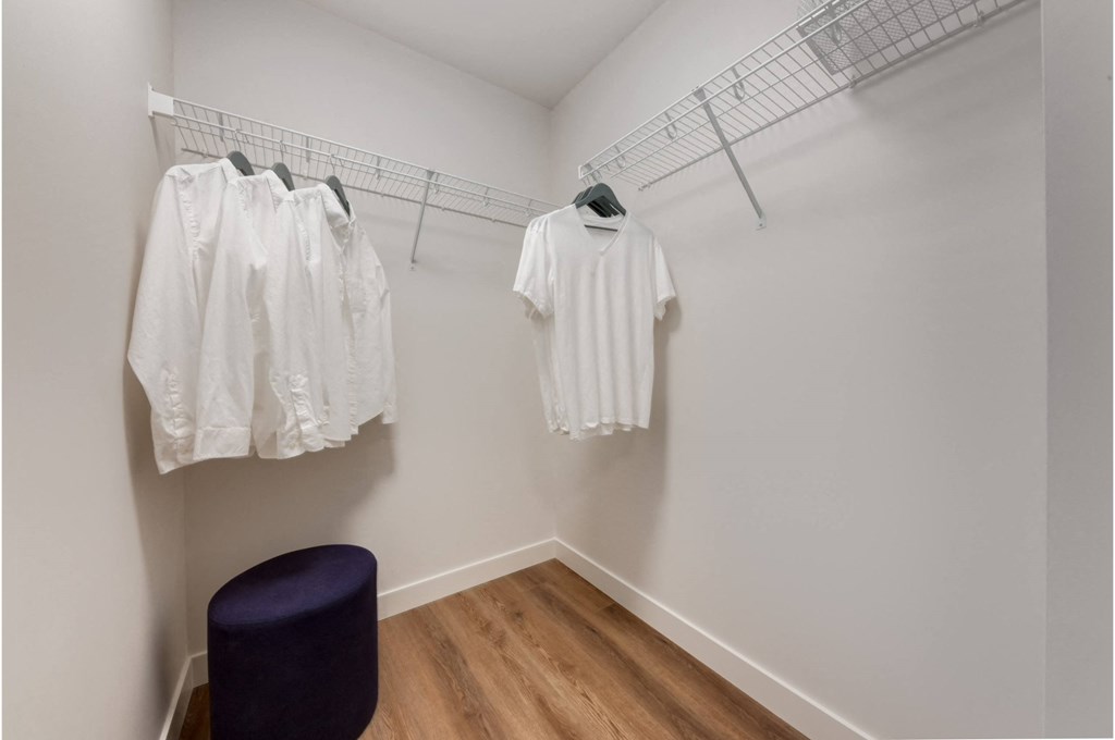 A row of white shirts hanging on a rack in a room.