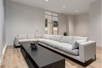 A white sofa with a black coffee table in front of it.