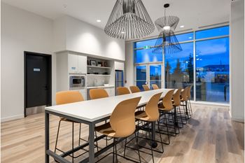 A modern dining room with a long table and chairs.