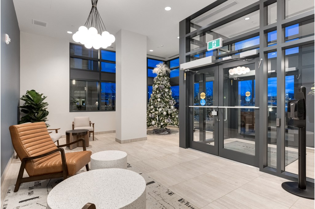 A modern waiting area with a chair, table, and a tree.