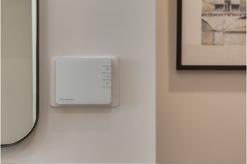 A white device with buttons is mounted on a wall.