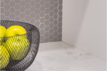 A black wire basket with three yellow balls inside.