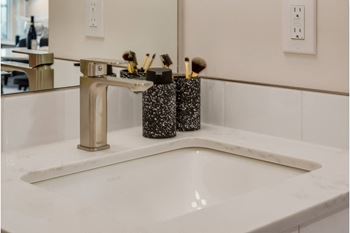 A bathroom sink with a silver faucet and two black and white containers on it.