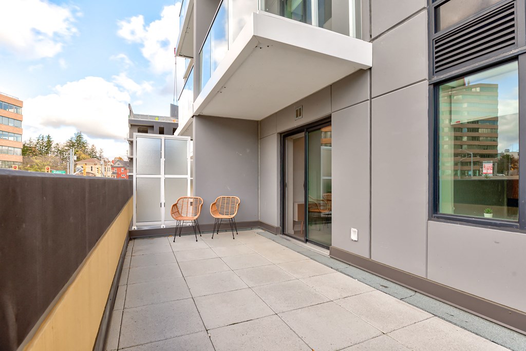 a patio with two chairs and a building in the background