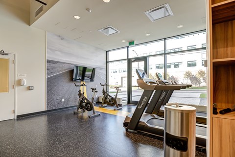 a gym with treadmills and other exercise equipment in a building with large windows