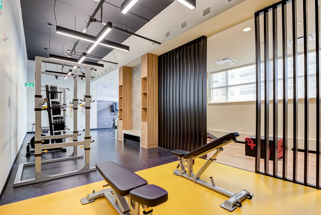 the gym has a large window and weights machines and yoga mats