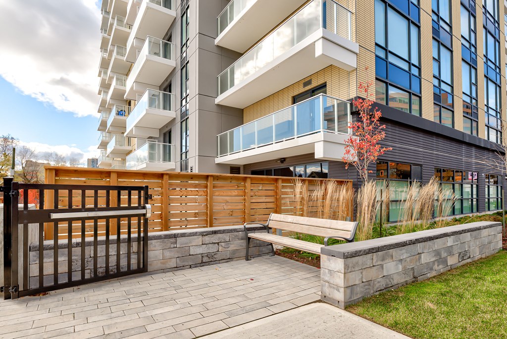an outdoor patio with a bench in front of an apartment building