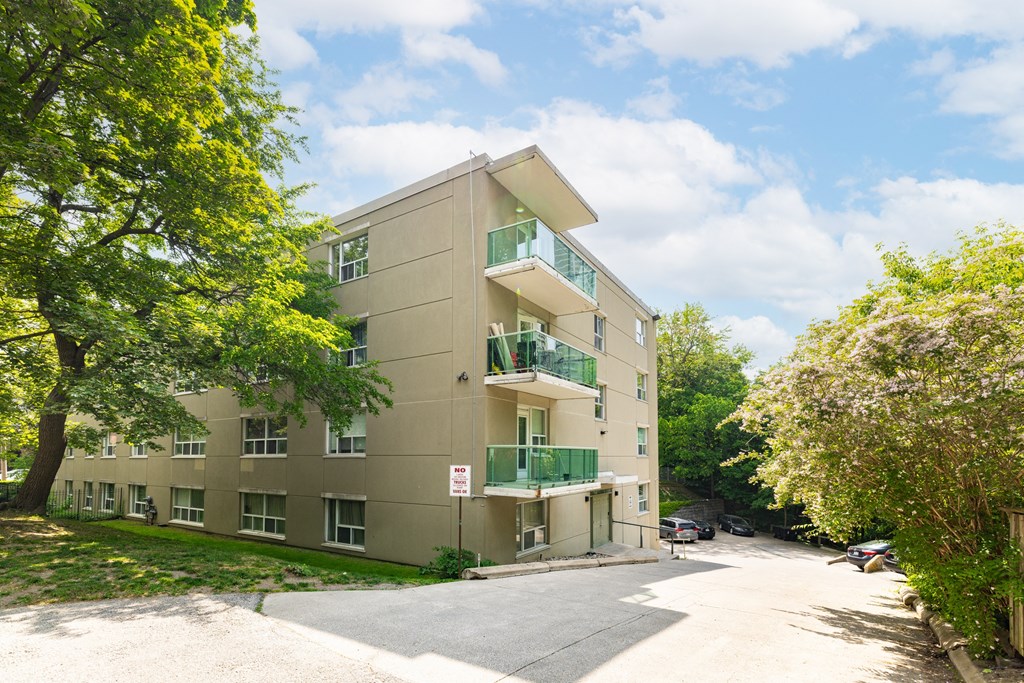 an apartment building with a driveway and trees in front of it