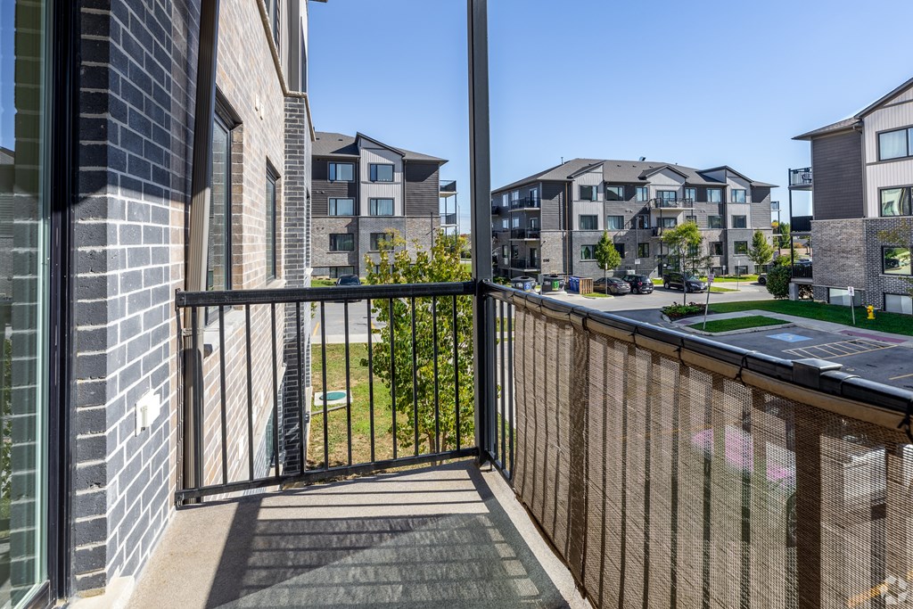 A black gate leads to a green lawn in front of apartment buildings.