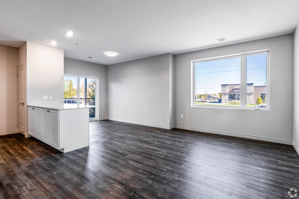 A large empty room with a window overlooking a residential area.