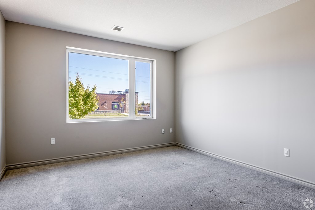 A room with a large window and a view of a street and buildings outside.