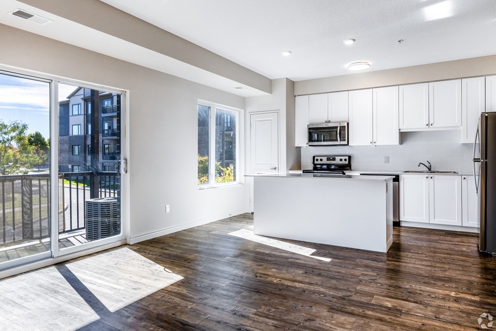 A modern kitchen with white cabinets and a wooden floor.