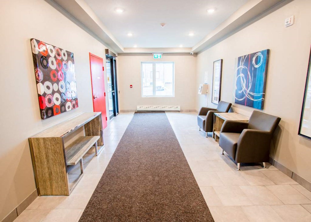 a hallway with chairs and paintings on the wall and a carpet