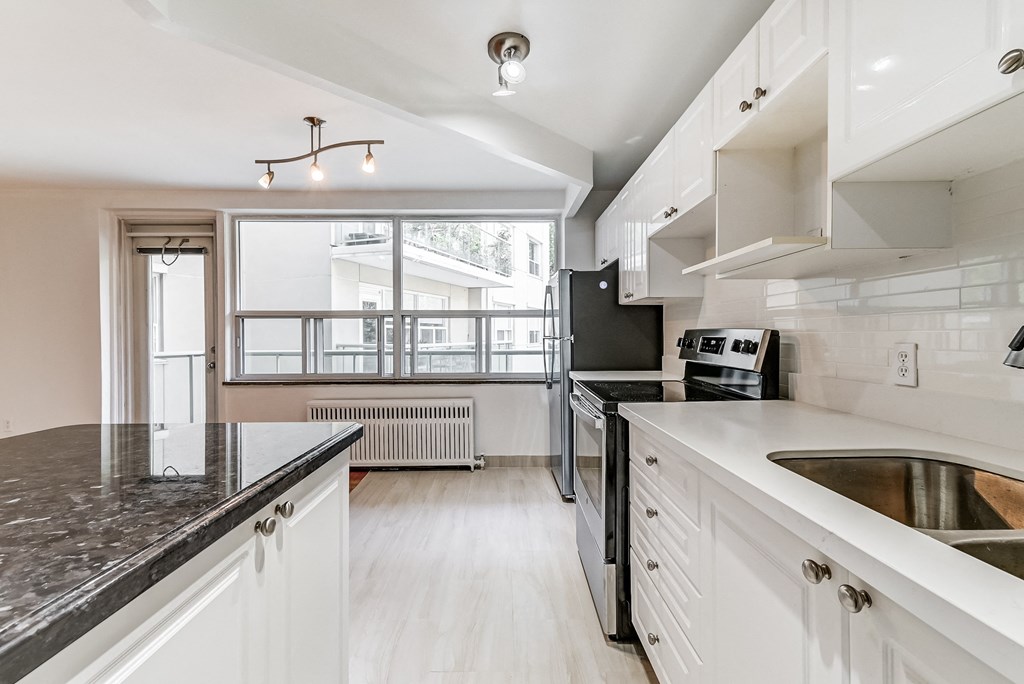 a kitchen with white cabinets and black counter tops