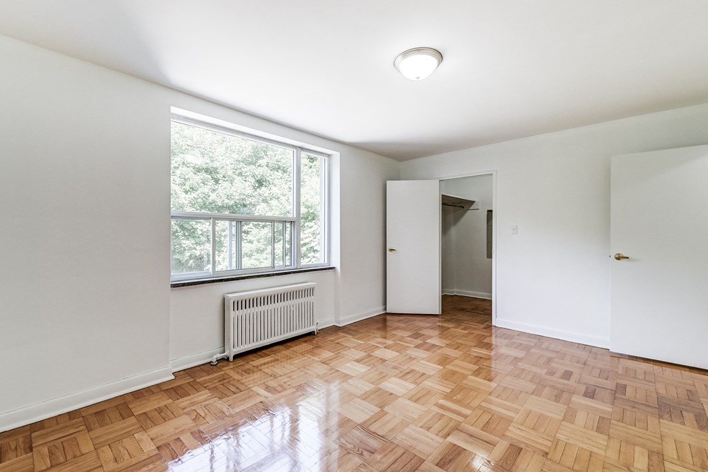 an empty living room with a large window and wooden floors