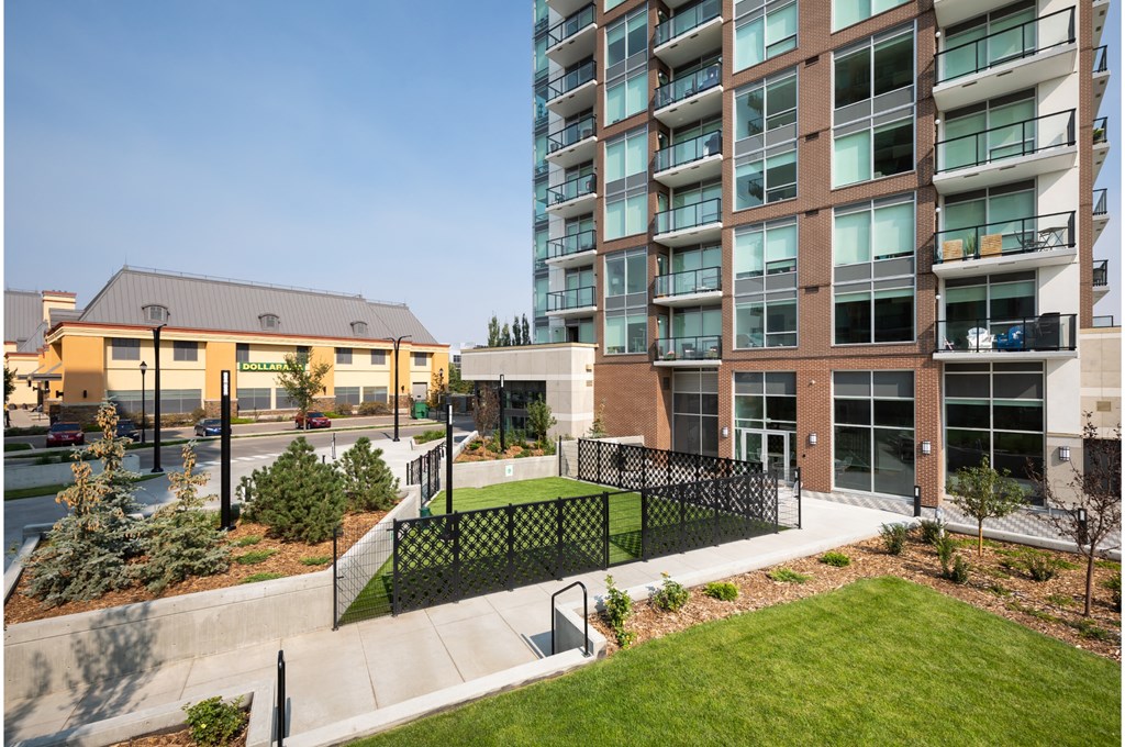 A modern building with a black fence and a green lawn in front.