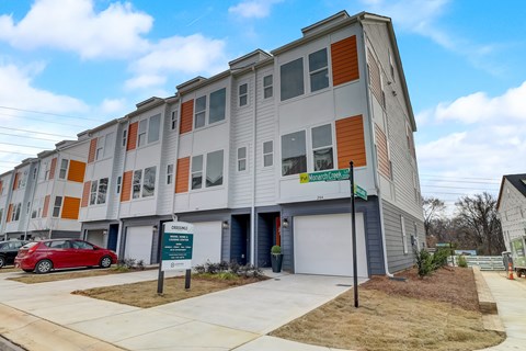 A modern apartment building with a red car parked in front.