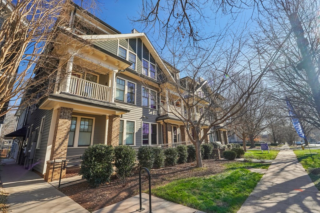 A row of houses with a sidewalk in front.
