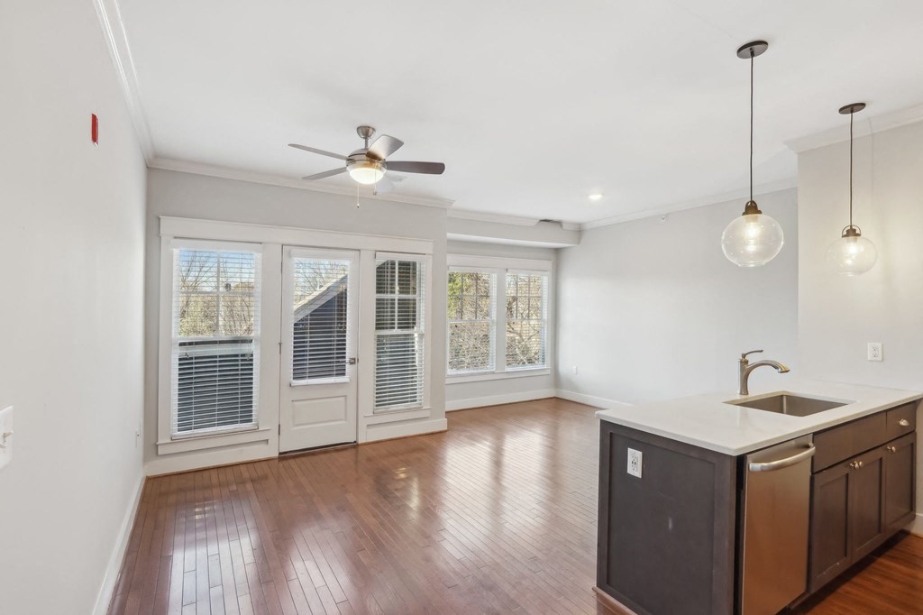 A kitchen with a fan on the ceiling and a sink in the middle.
