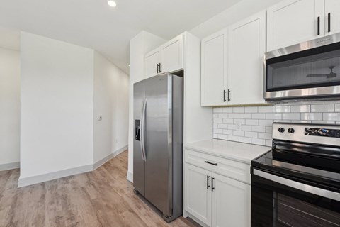 A kitchen with a stainless steel refrigerator, microwave, and oven.