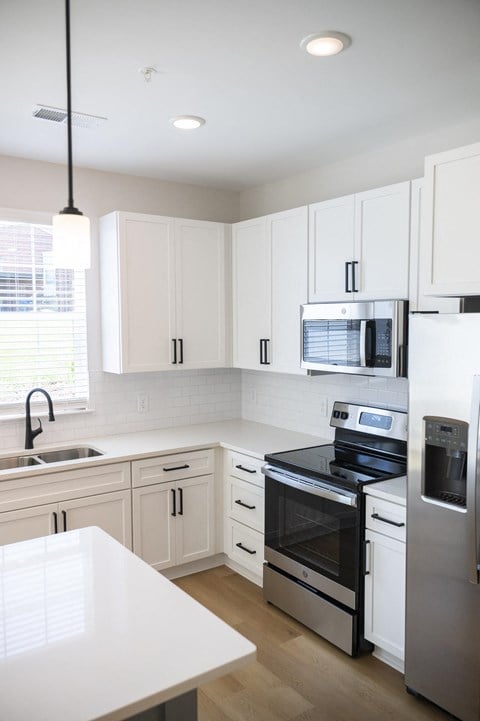 a kitchen with white cabinets and stainless steel appliances at Landon Green Artisan Cottages Apartments, North Carolina