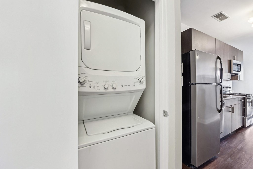 A white dishwasher is in a kitchen next to a black refrigerator.