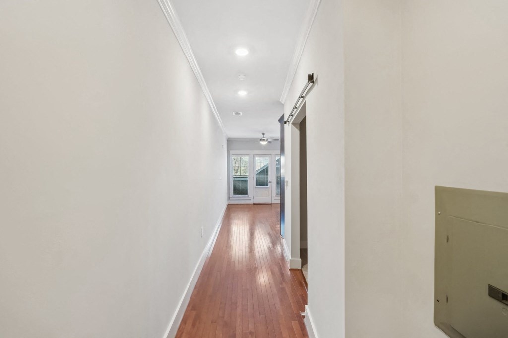 A long hallway with wood floors and white walls.