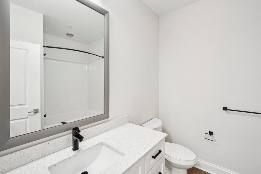 A white bathroom with a sink, toilet and mirror.