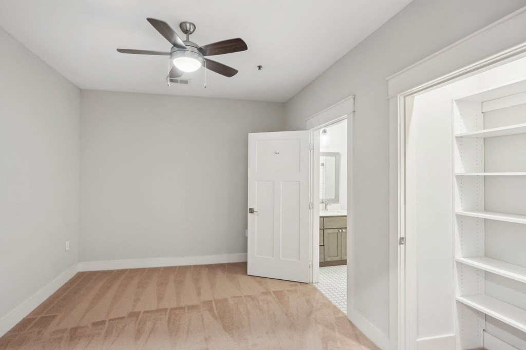A room with a ceiling fan and wooden flooring.