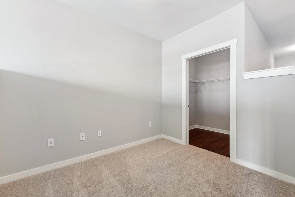 A room with a carpeted floor and a door leading to another room.