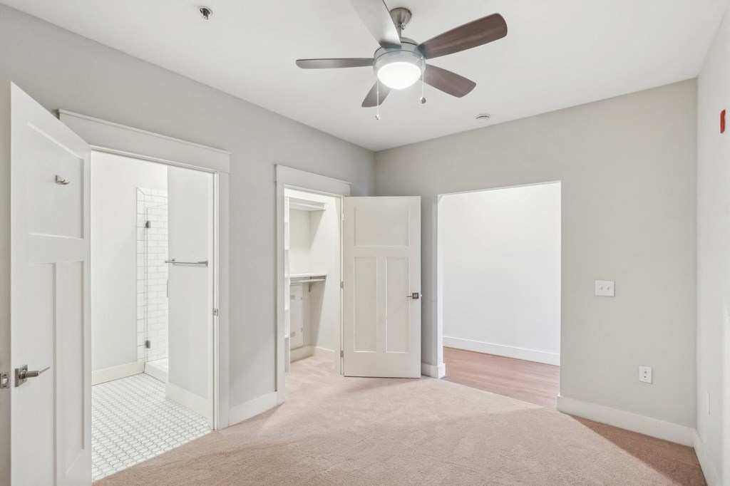 A room with a ceiling fan and a rug on the floor.