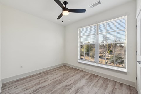 A room with a ceiling fan and a window with blinds.