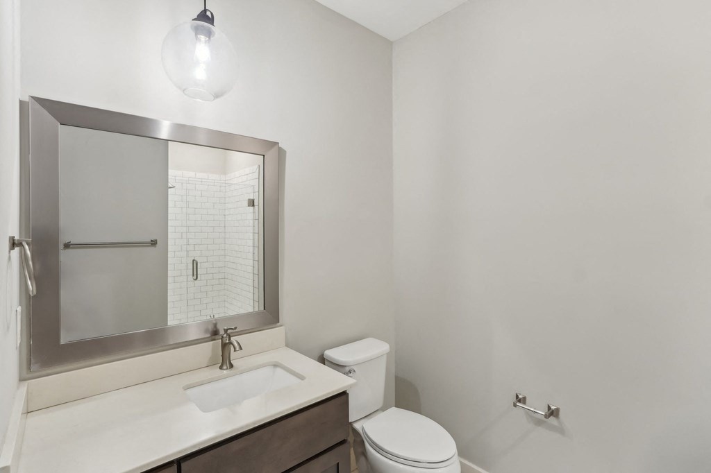 A white bathroom with a toilet, sink, and mirror.