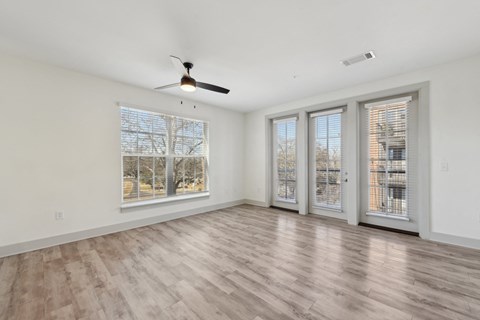 A room with a ceiling fan and sliding glass doors.