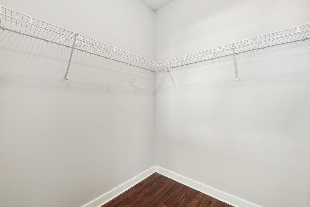 Empty room with a white wall and a wooden floor.