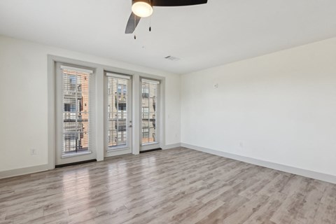A room with a ceiling fan and three windows.