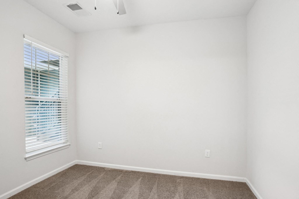 A room with a window and a carpeted floor.