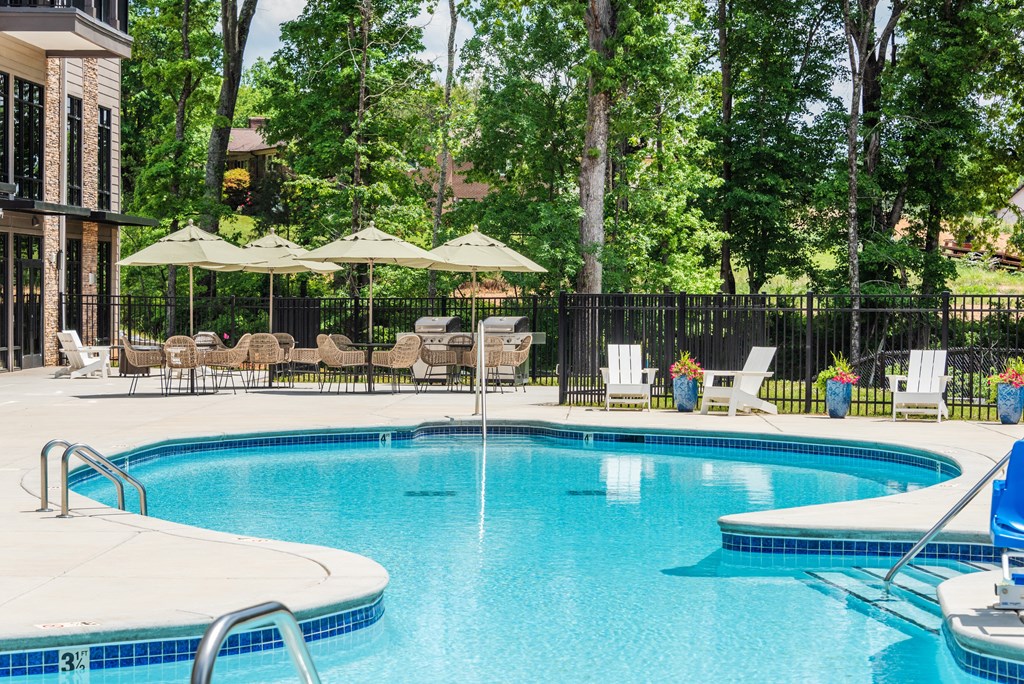 a swimming pool with chairs and umbrellas in front of a resort style pool