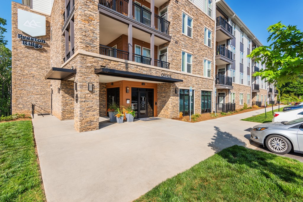 an apartment building with a driveway and a car parked next to it